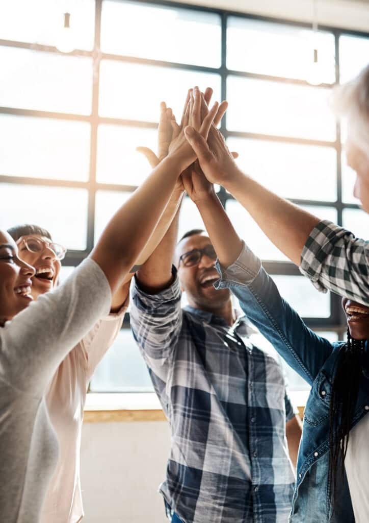 Staff smiling, celebrating, and high fiving in a modern office building.